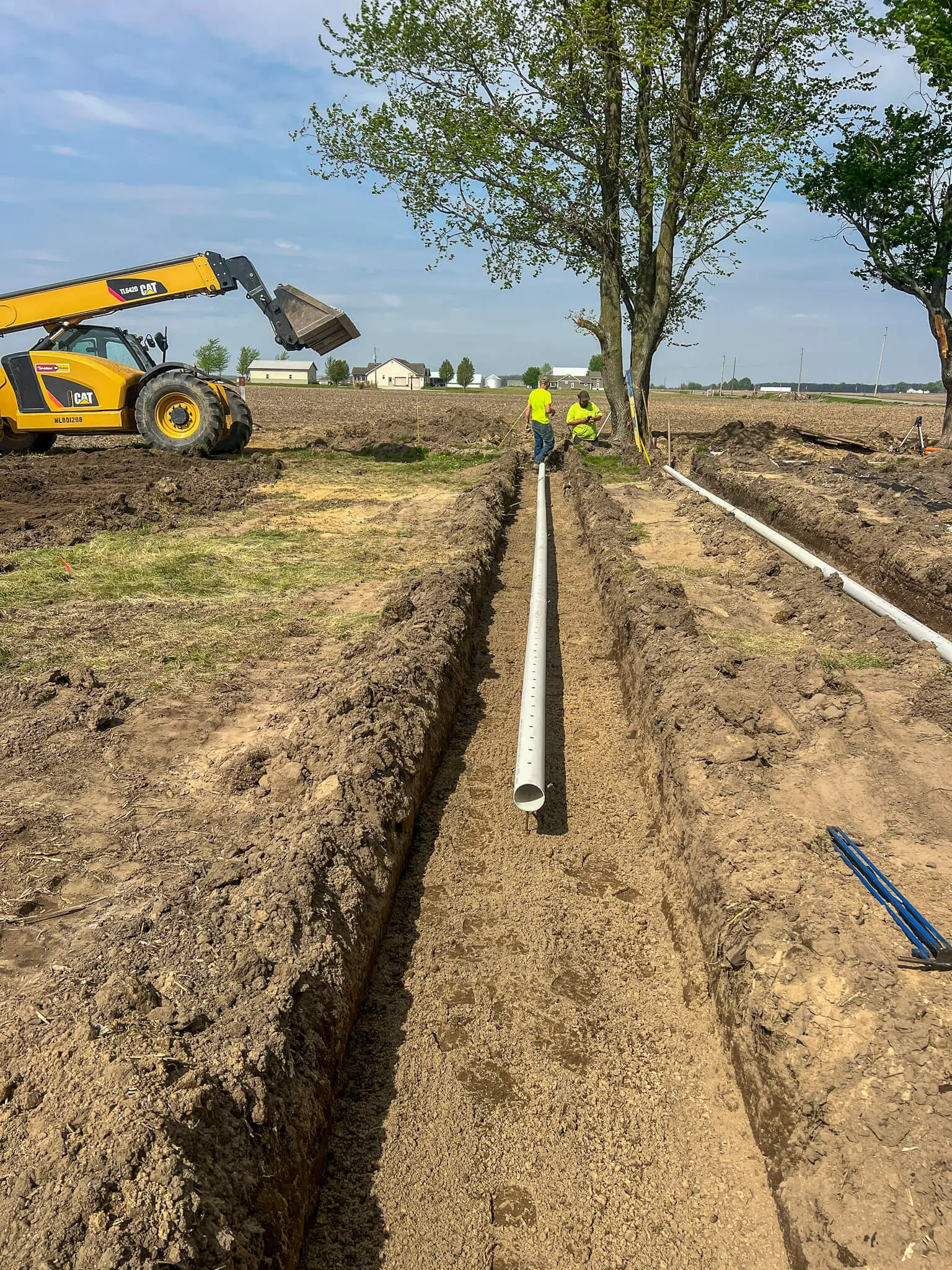 Crew laying drain tile pipe in a farm field
