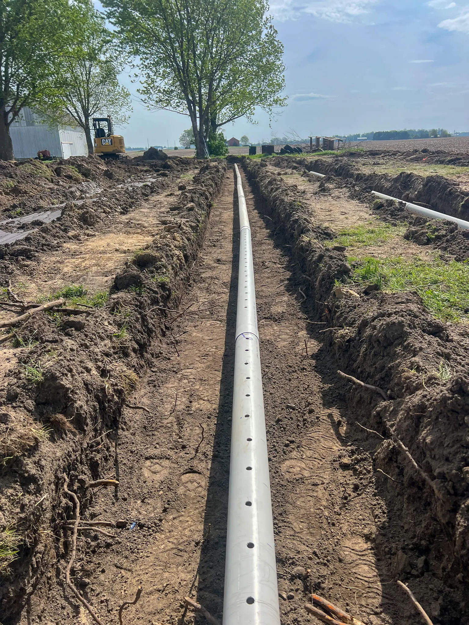 New drain tile laid in a farm field trench