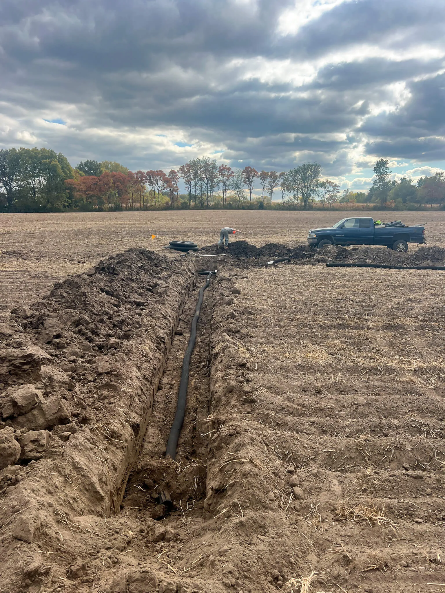 Farm tile trench with the crew running new drainage pipe
